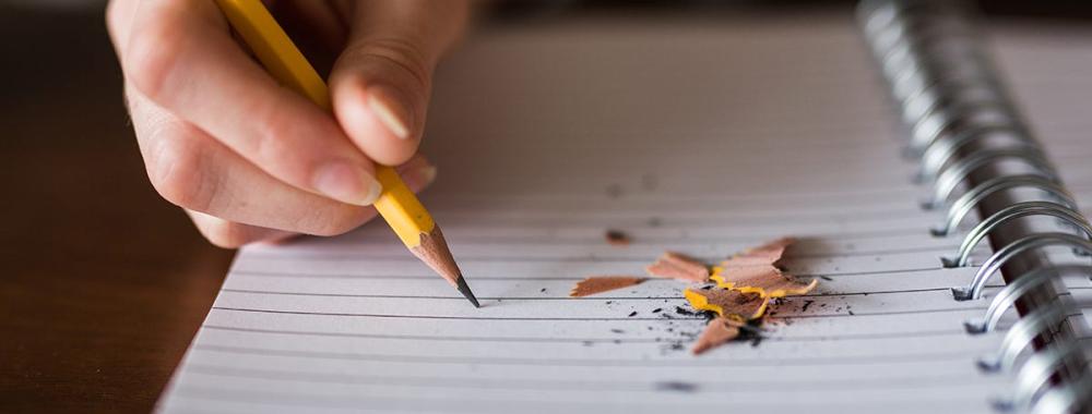 Person with pencil writing on paper