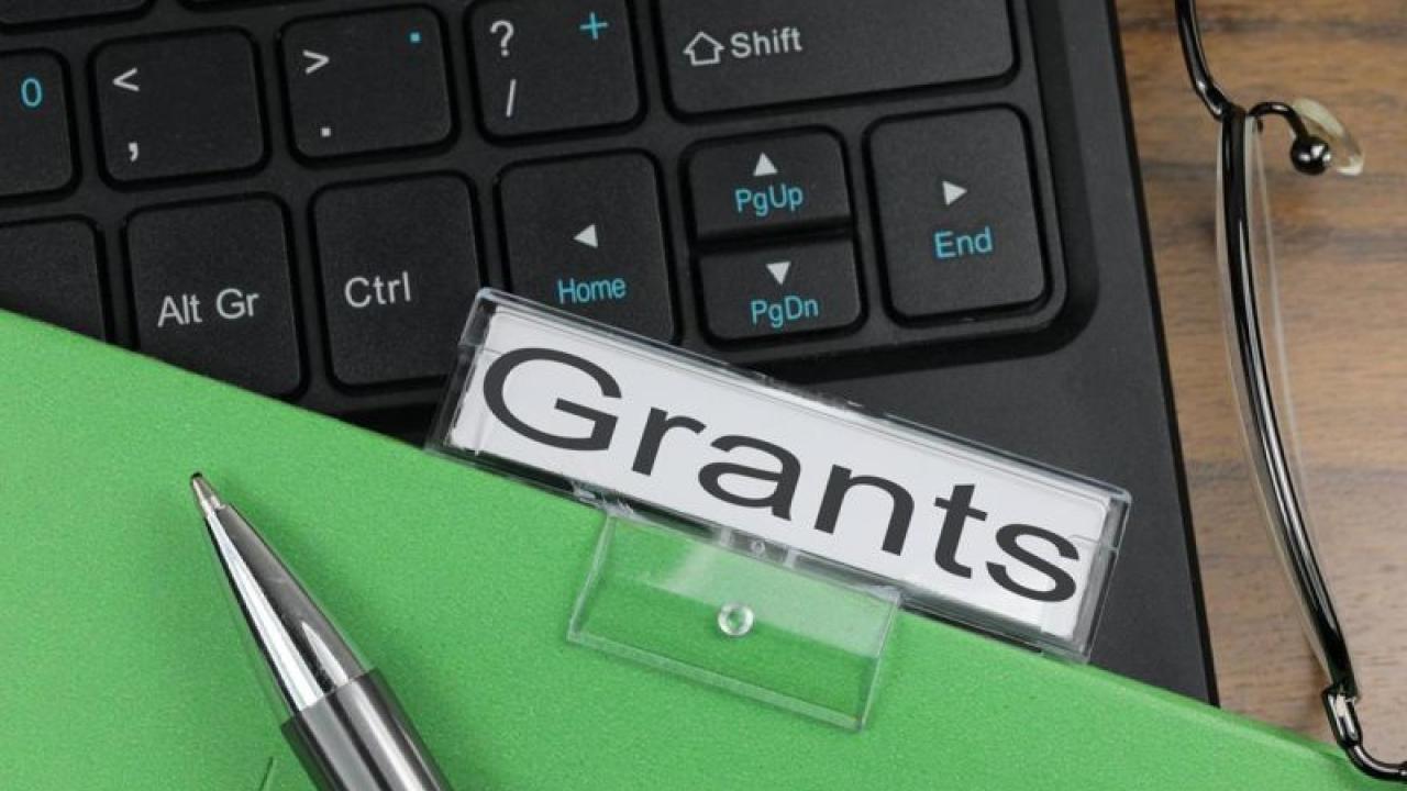 Keyboard overlaid with file folder with a Grants label
