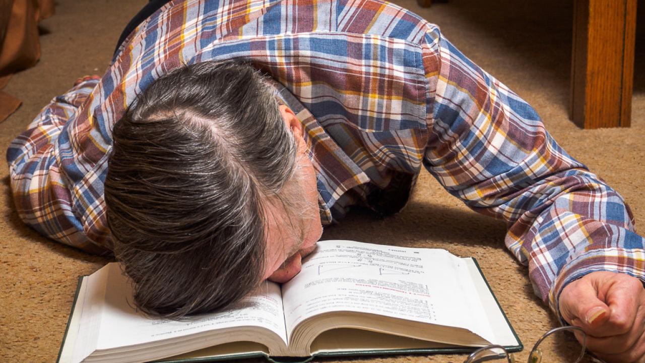 Man asleep with face in a book.