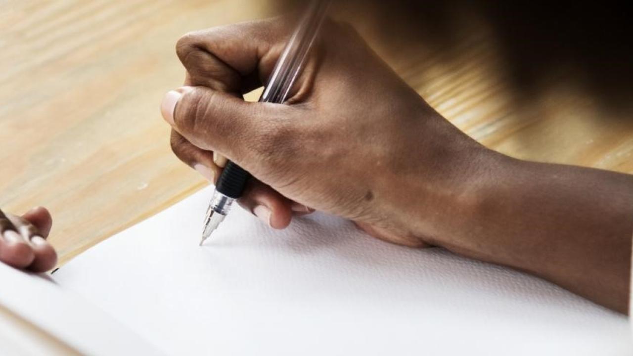 Person's hand with pen and paper