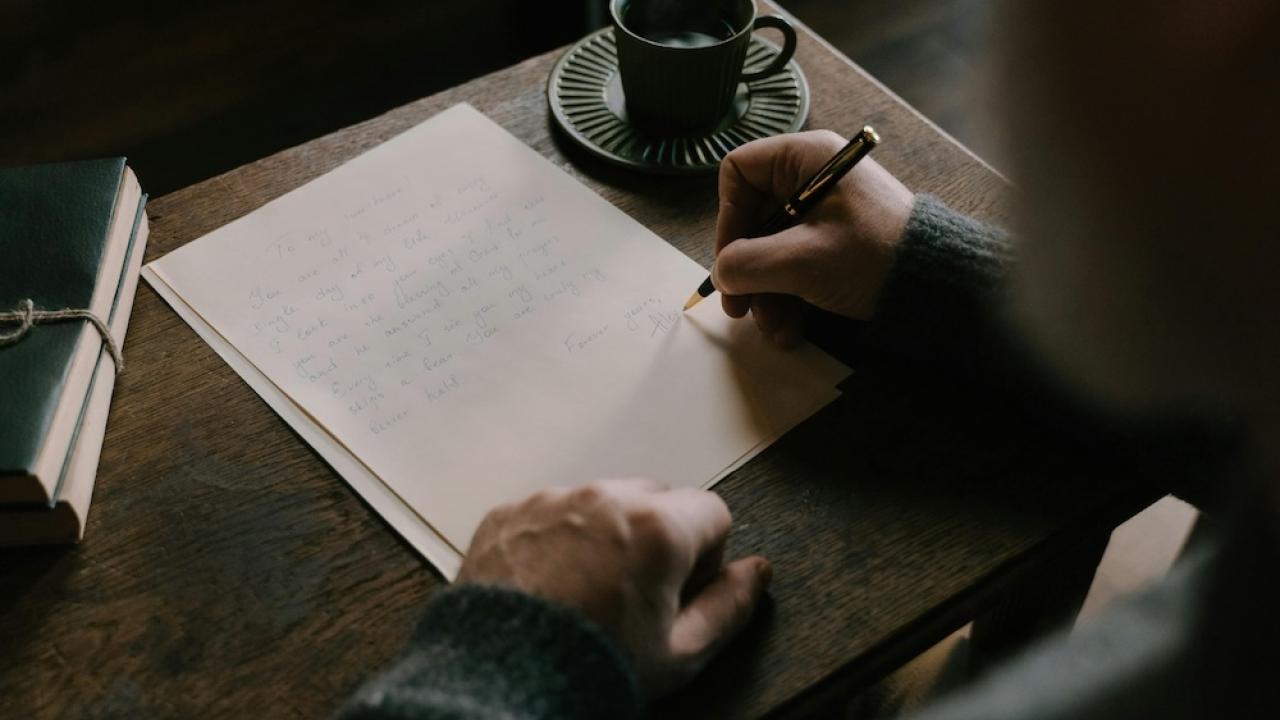Person's hand writing with desk and paper