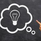 Lightbulb in thought bubble with hand pointing at it.