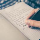 Person's hand writing a checklist with pen.