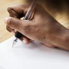 Person's hand with pen and paper