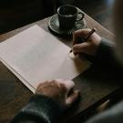 Person's hand writing with desk and paper